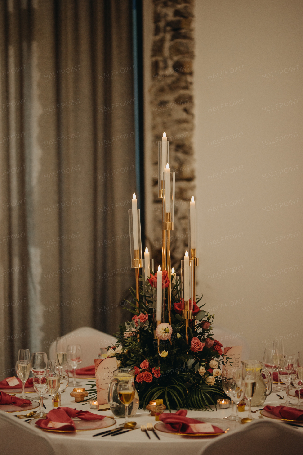 Elegant, romantic table setting for indoor wedding reception, celebration. Luxury wedding table decoration, special event table set up with fresh flowers arragements and high candlestick, candle holder.