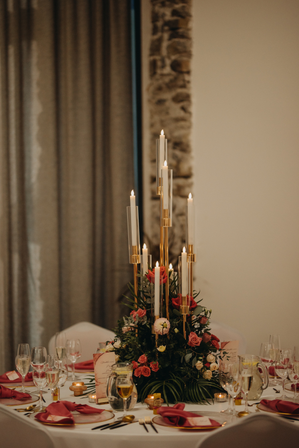 Elegant, romantic table setting for indoor wedding reception, celebration. Luxury wedding table decoration, special event table set up with fresh flowers arragements and high candlestick, candle holder.