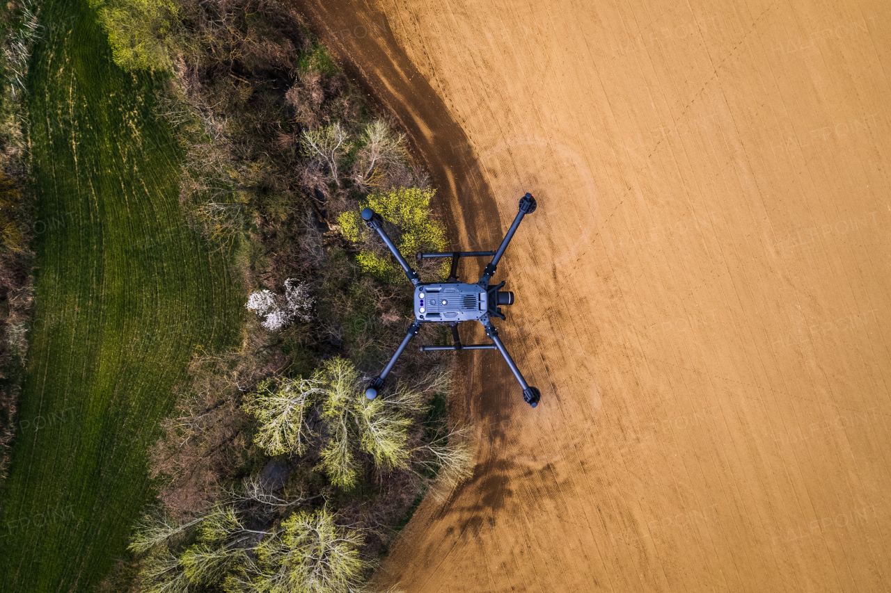 Aerial view of a drone flying over green summer farm fields, crops or pasture with road and mountains.