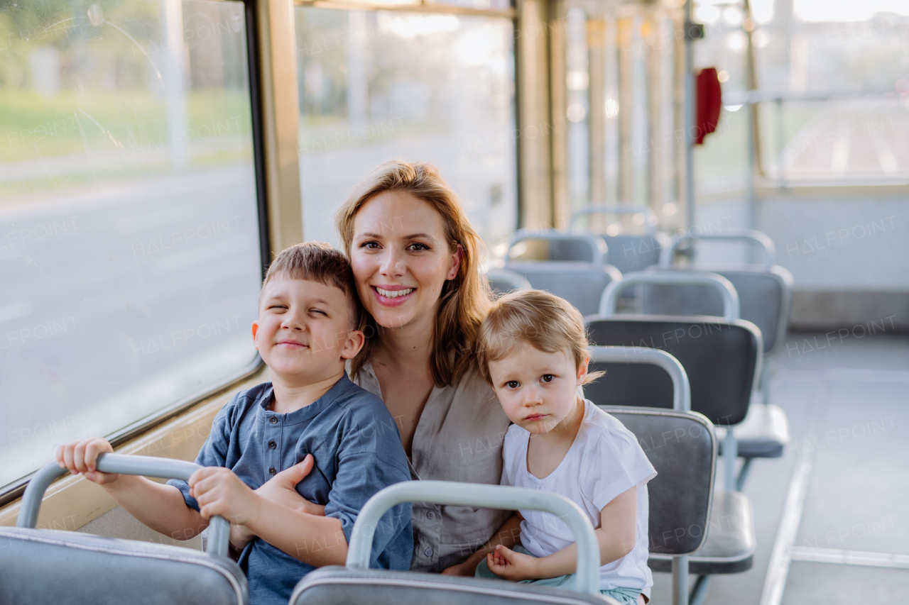 A young mother with little kids travelling in tram in summer, commuting and sustainable lifestyle concept.