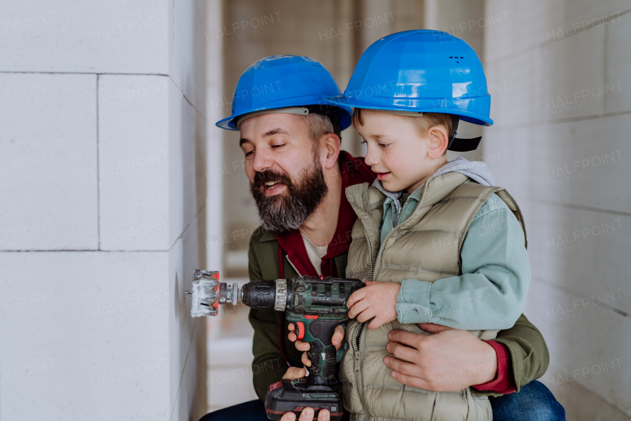 Father and his little son working together on their unfinished house.