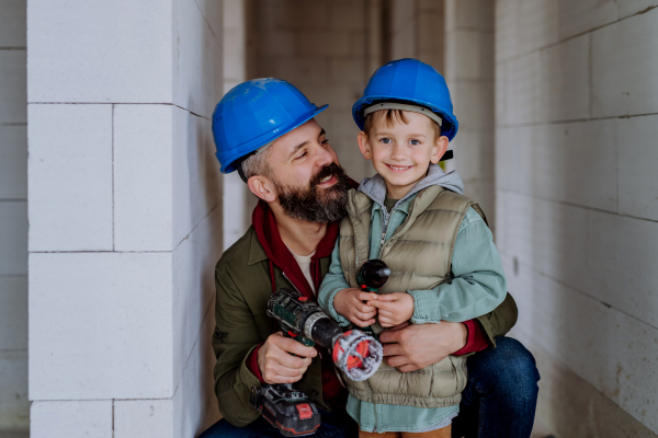 Father and his little son working together on their unfinished house.