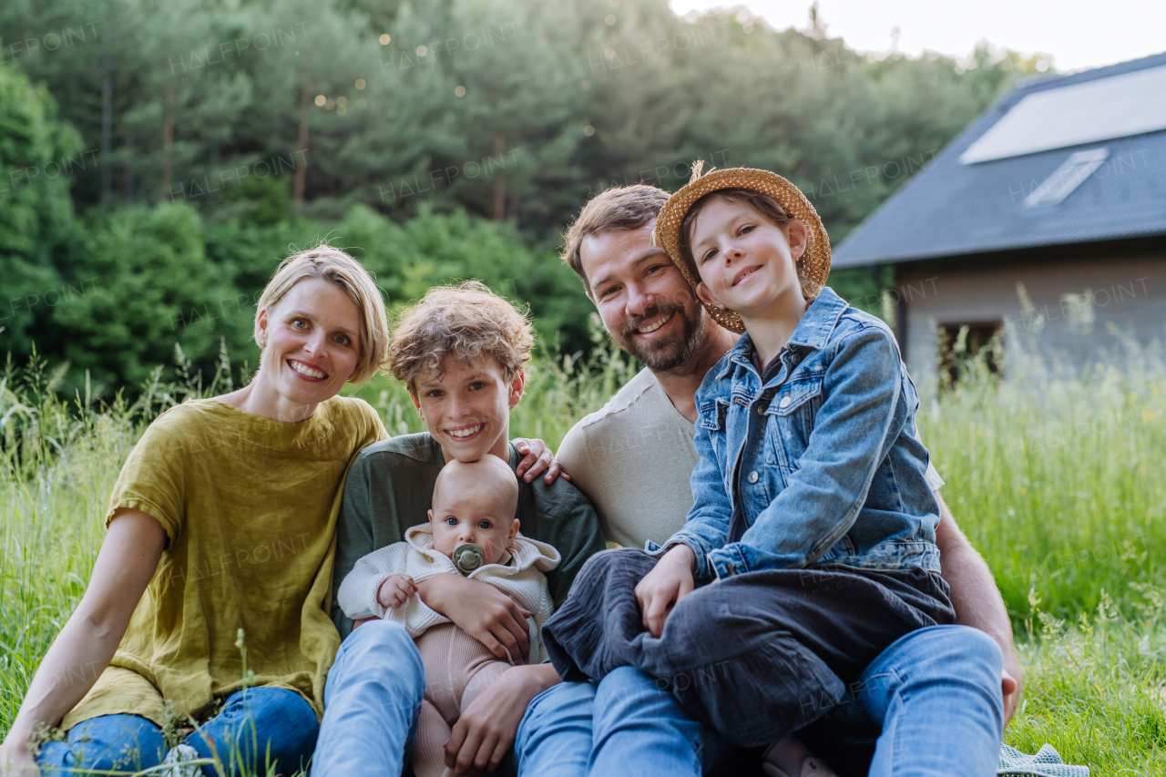 Happy family near their house with a solar panels. Alternative energy, saving resources and sustainable lifestyle concept.