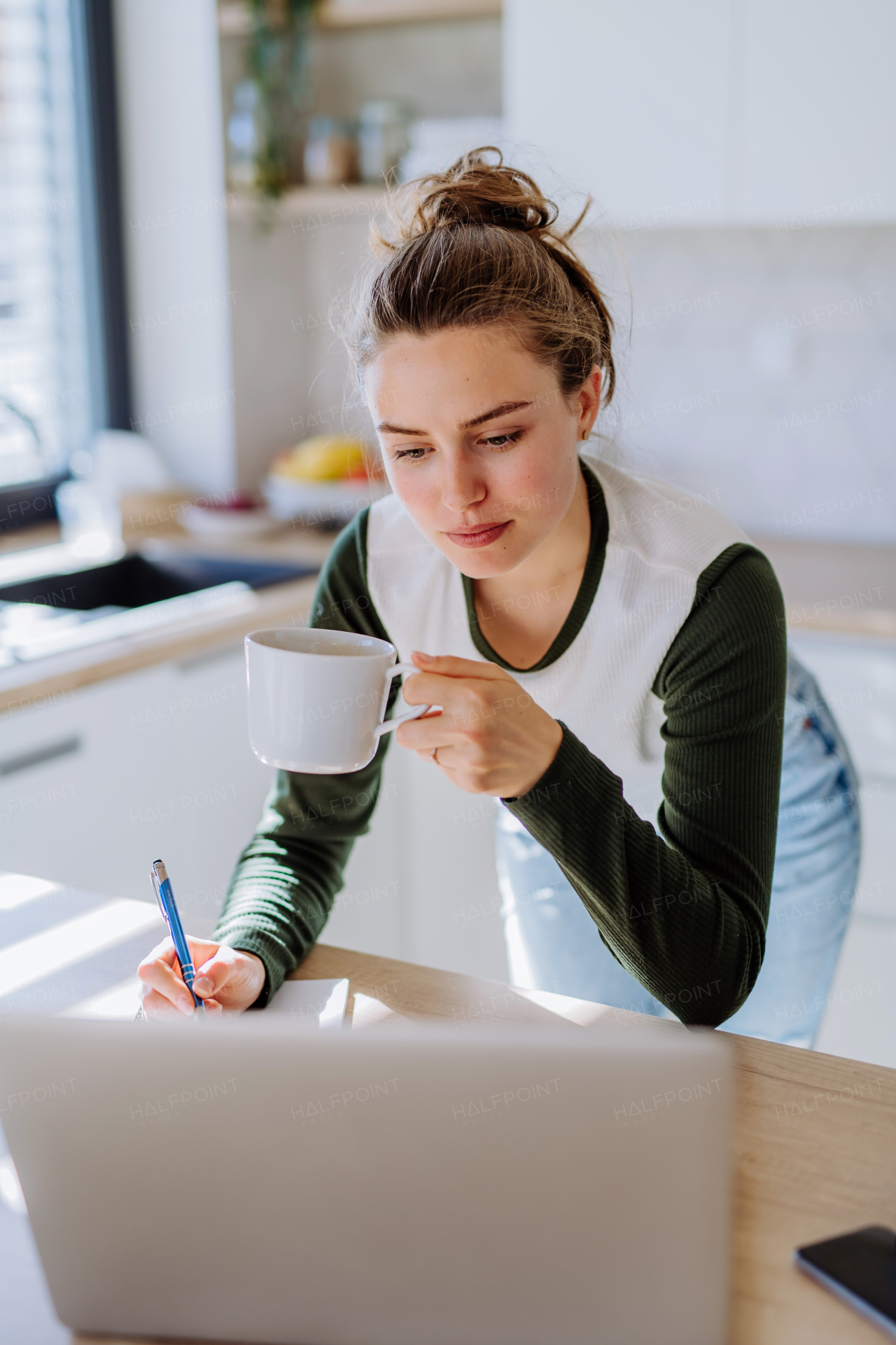 Young woman having homeoffice in a kitchen.