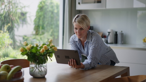 A beautiful woman adjusting smart home settings on touch screen device. Smart home technology for sustainable living.