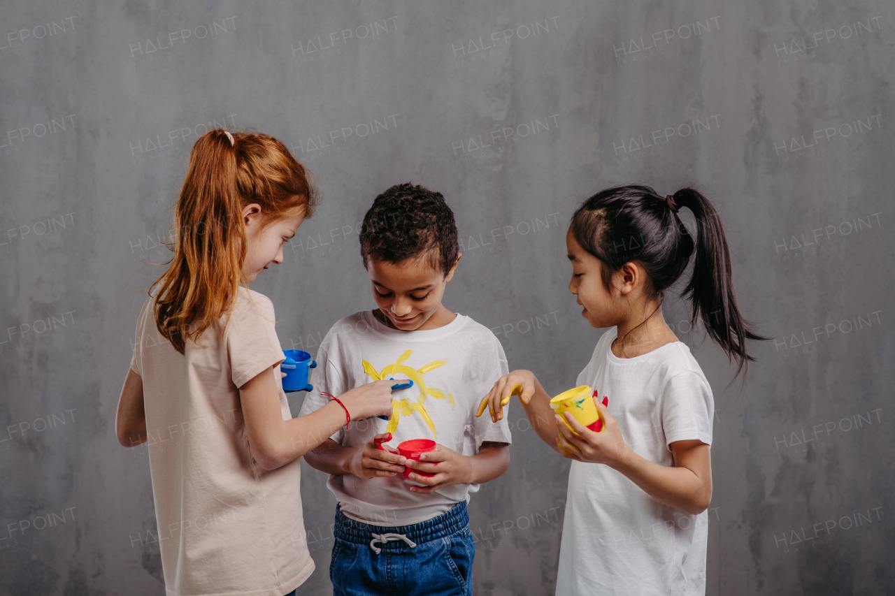 Portrait of happy kids with finger colours and painted t-shirts.
