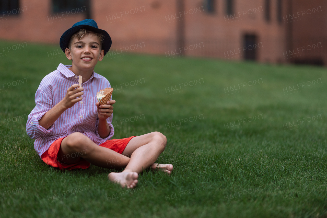 Little boy sitting in city park and eating ice cream.