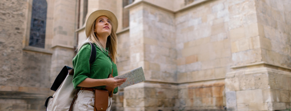 Young blond woman travel alone in old city centre. Wide photography.