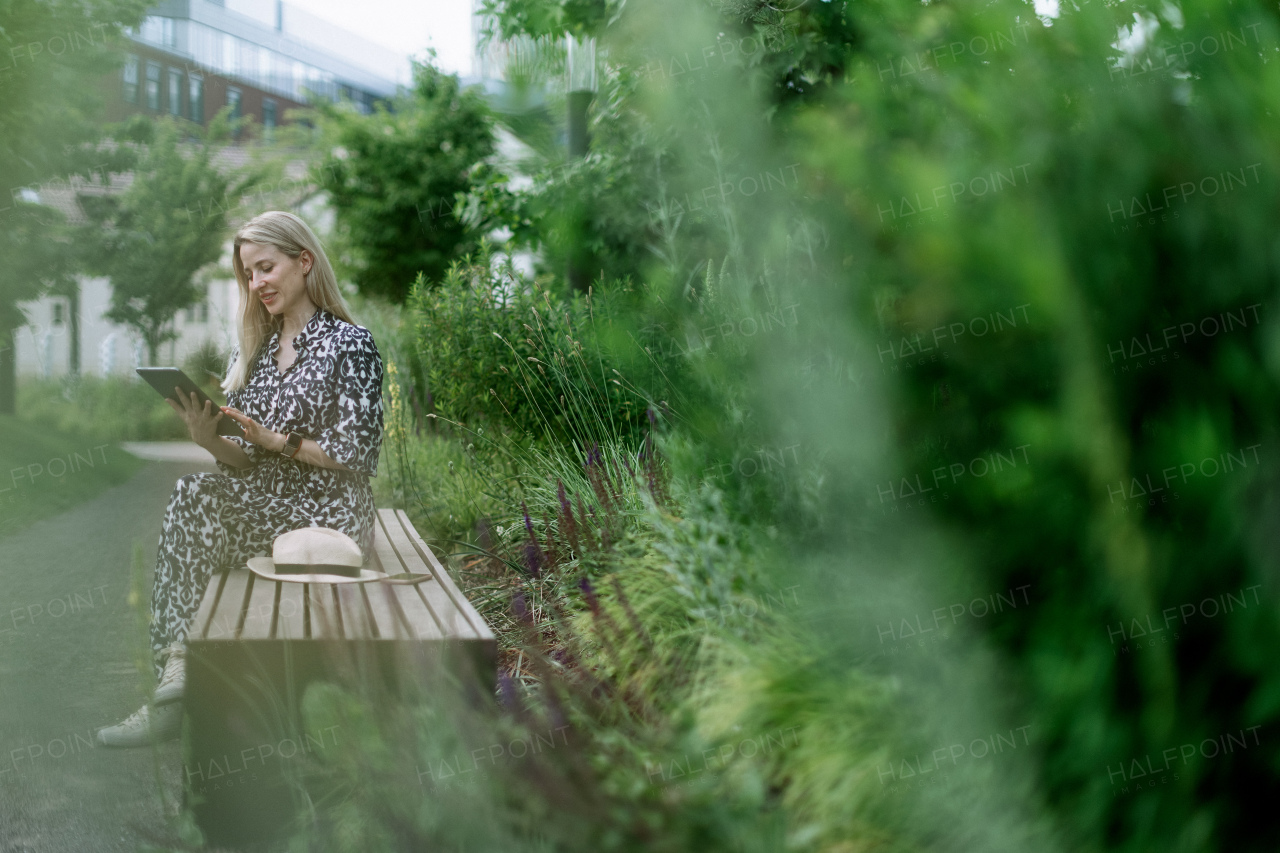 Mature woman sitting in a park bench, enjoying time for herself.