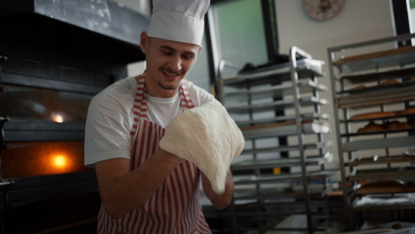Young baker with down syndrome preparing pastries in bakery. Concept of integration people with a disabilities into society.