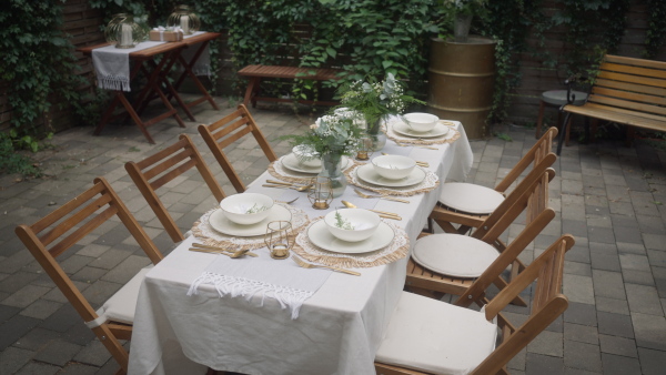 A festive wedding table setting with flowers at small reception in backyard in summer.