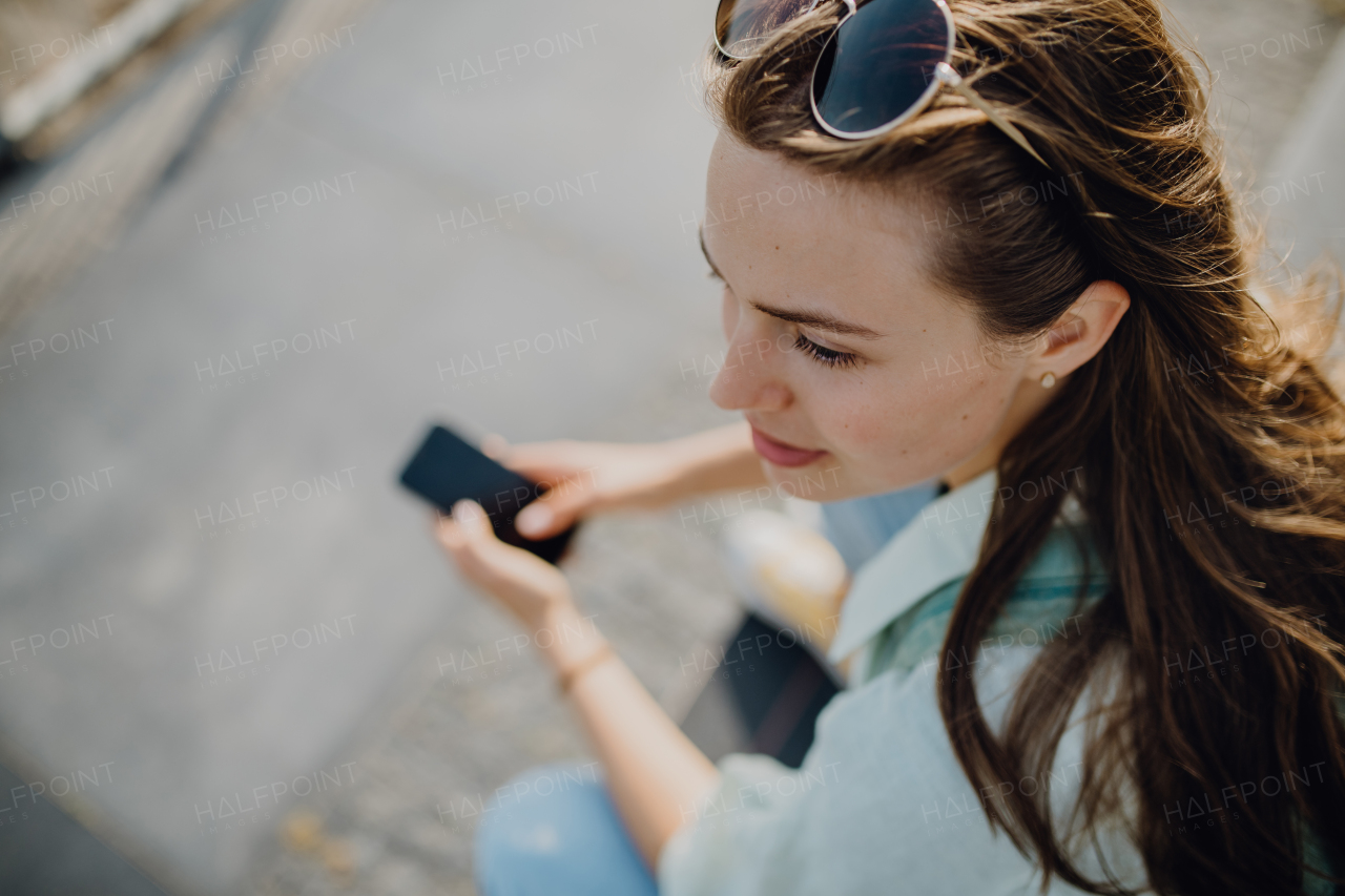 High angle view of young woman with smartphone outdoor in city.