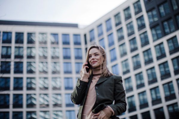 Portrait of young fashionable woman in city calling.