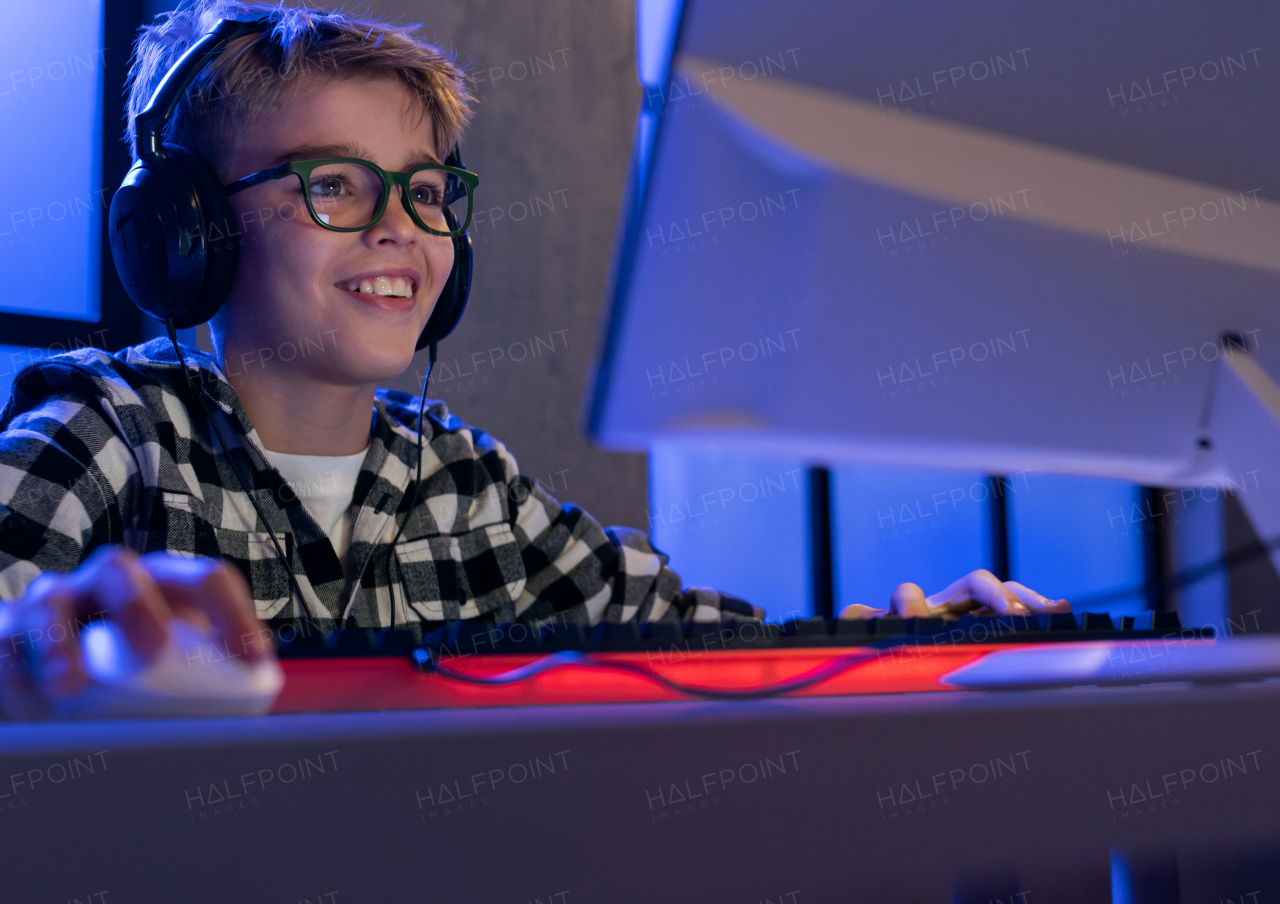 A young gamer boy with headphones playing computer video game.