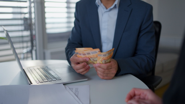 A businessman giving money to his partner while making contract - bribery and corruption concepts