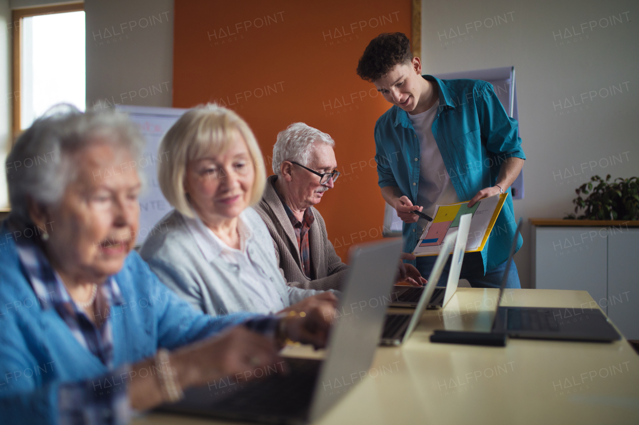 A senior group in retirement home with young instructor learning together in computer class