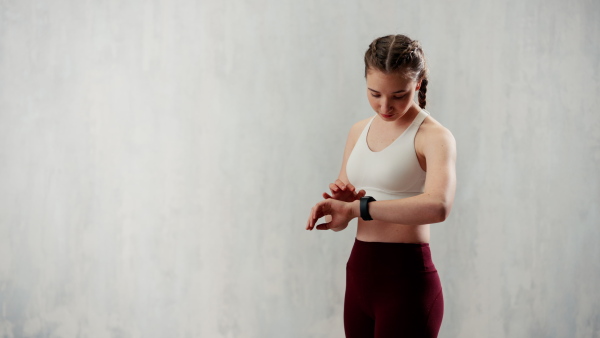 A young woman setting and looking at sports smartwatch. Fitness female checking her performance.
