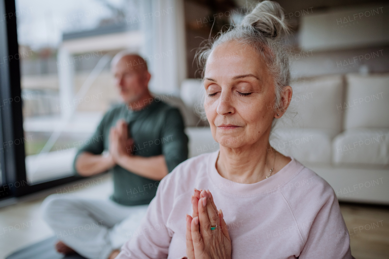 A senior couple doing relaxation exercise together at home.
