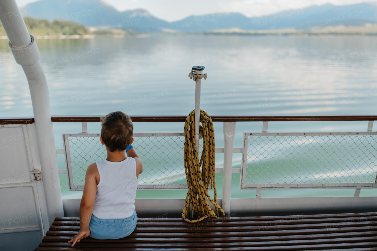 A little curious boy looking at water from motor boat.