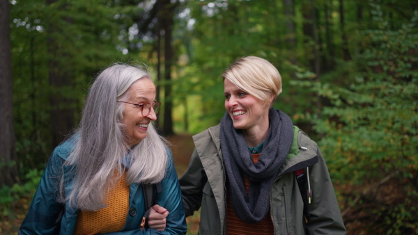 A senior mother with daughter on walk outoors in forest.