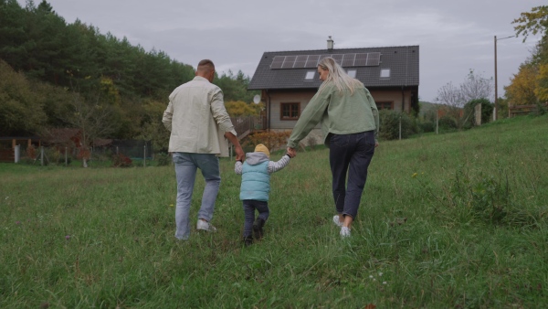 Family house with rooftop solar panels. Young family in front of their solar-powered home.