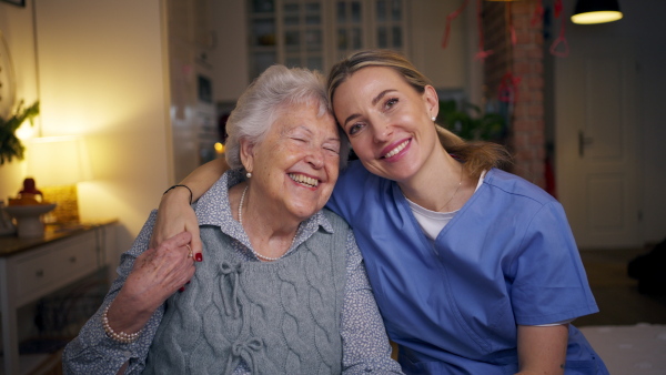 Caring healthcare worker visiting a senior patient at home, hugging her