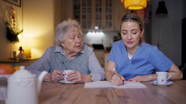 Social worker helping elderly lady with managing her finances and cworking on