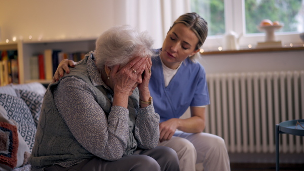 Nurse hugging elderly patient, mental health support and grief counseling to a senior woman.