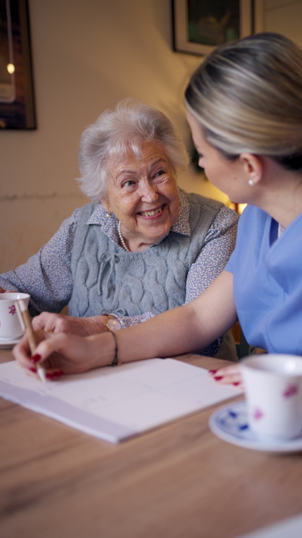 Social worker helping elderly lady with managing her finances and cworking on