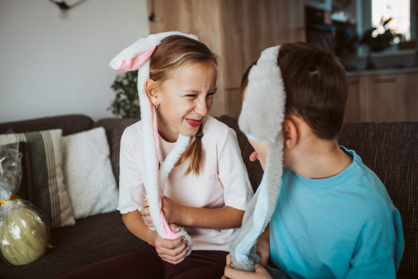 Brother and sister wearing bunny ear headbands. Siblings celebrating Easter.