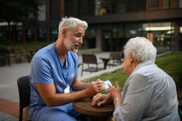 Doctor explaining medication to senior patient and answering her questions about diagnosis.