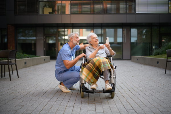 Male caregiver talking with senior woman in a wheelchair.