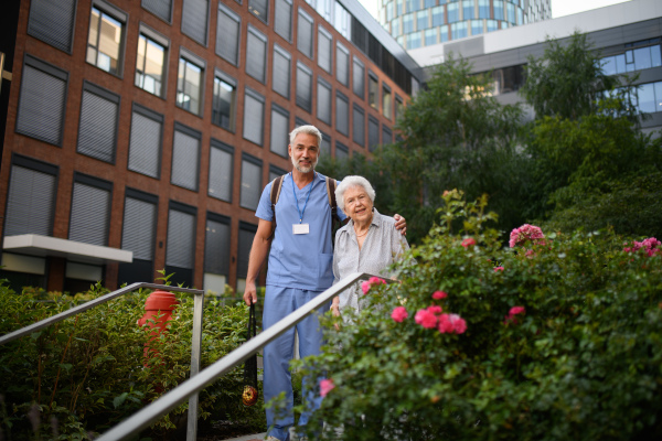 Caring healthcare worker helping elderly woman walk down the stairs.