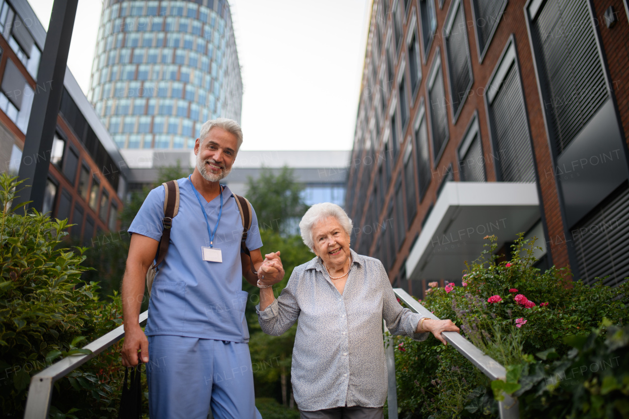 Caring healthcare worker helping elderly woman walk down the stairs.