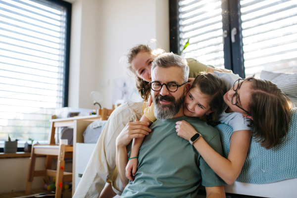 Portrait of father with three daughters at home. Girl dad concept.