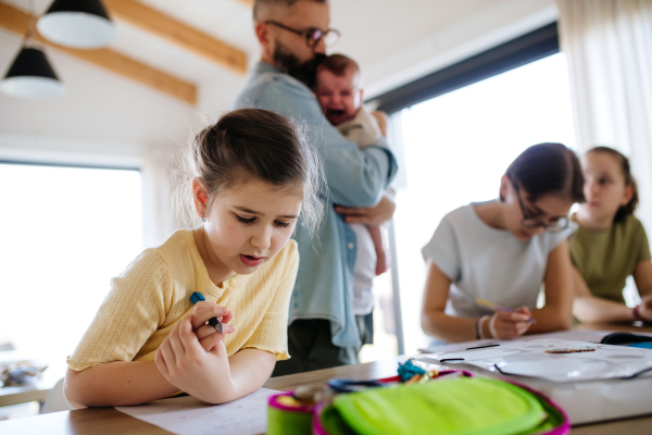 Father helping his daughters with homework while taking care of baby. Big family.