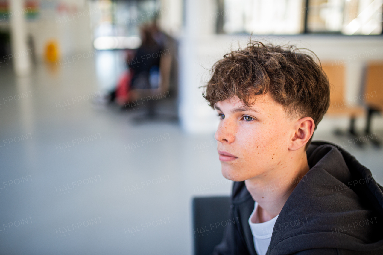 Teenage boy waiting alone in hospital waiting area before preventive medical checkup.