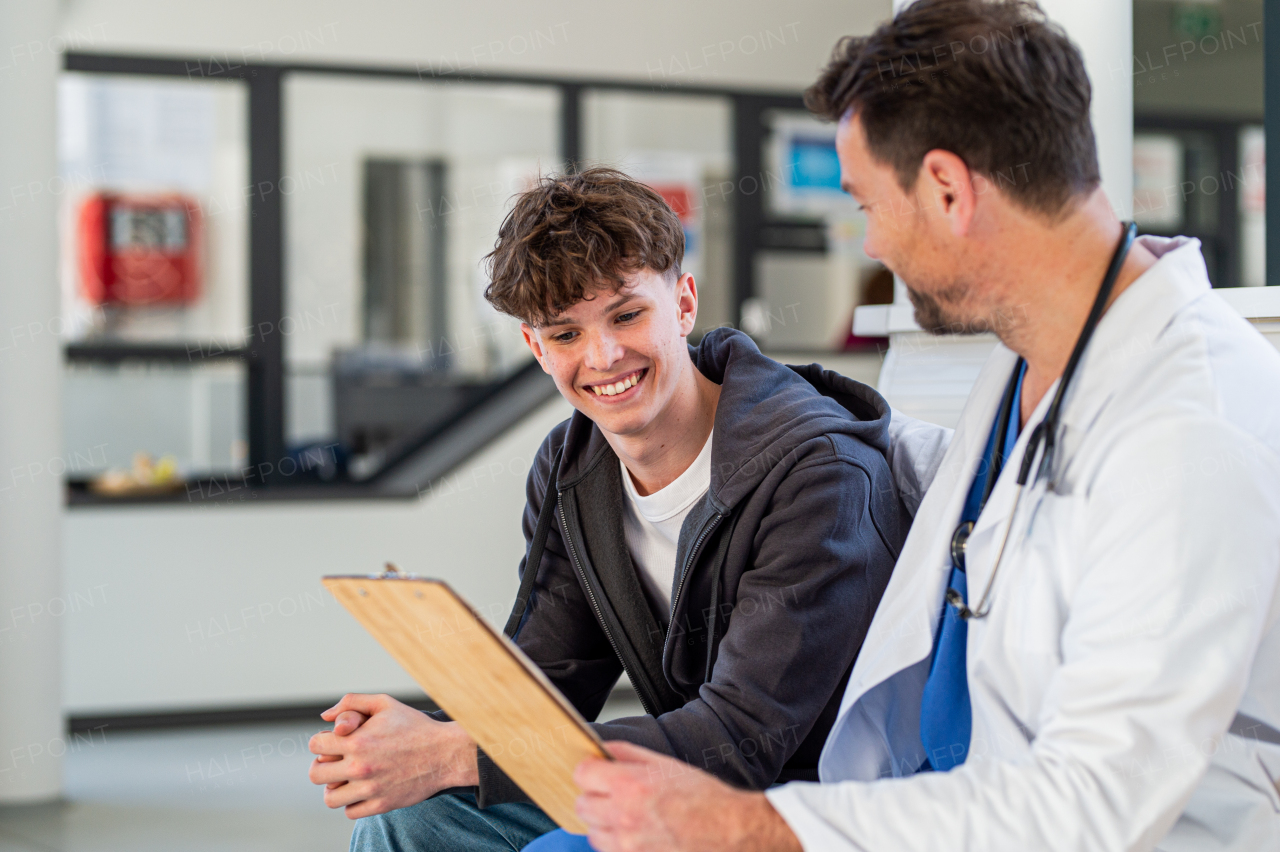 Teenage boy smiling talking with supporting doctor, receiving positive health news.