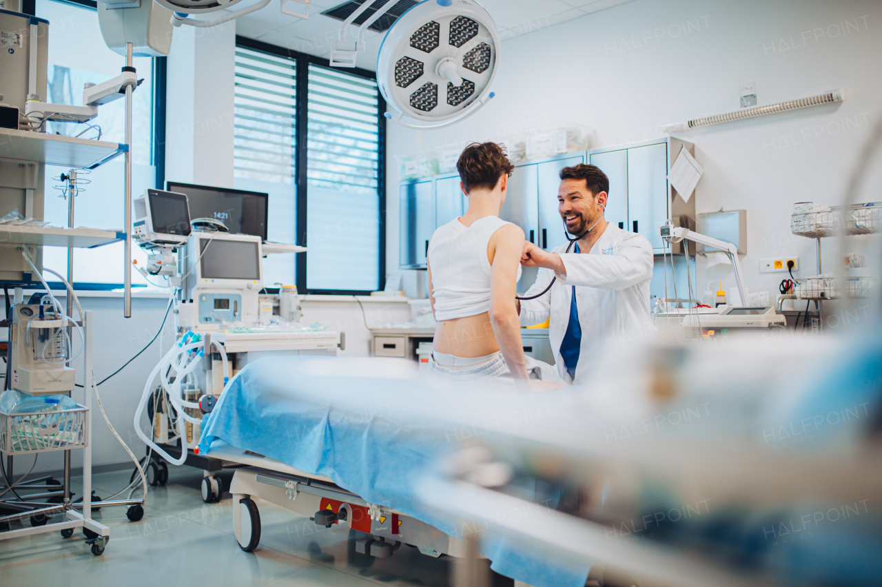 Teen boy undergoing medical checkup with smiling doctor in hospital room.