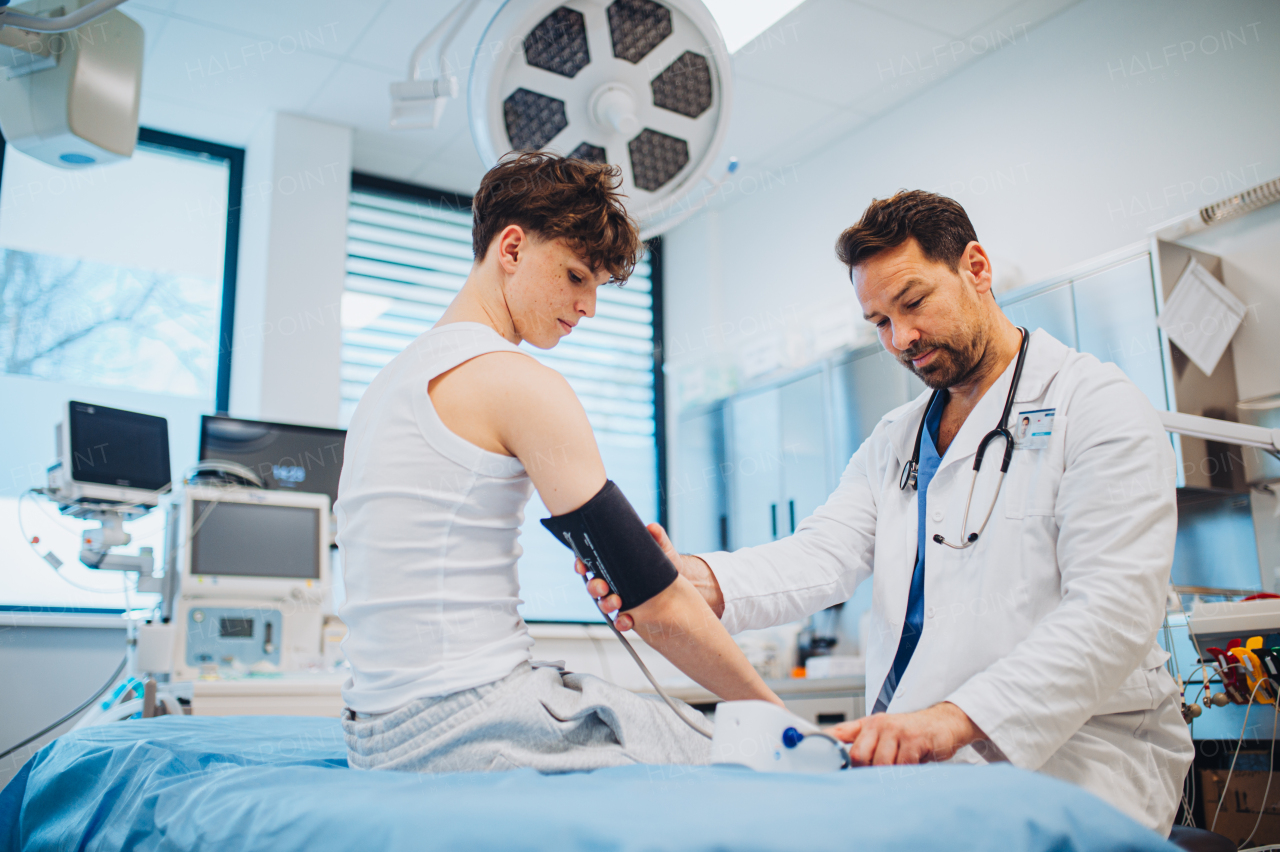 Teen boy undergoing medical checkup with smiling doctor in hospital room.