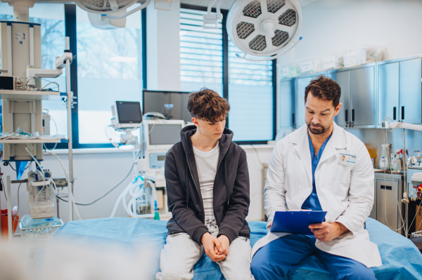 Empathetic doctor supporting teenage patient during health consultation, hospital setting.