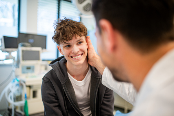 Teenage boy smiling during supportive medical consultation after receiving positive health news.