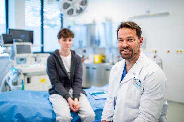 Portrait of doctor and teen boy during medical checkup in hospital room. Preventive care.