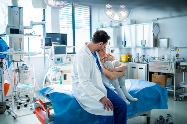 Compassionate doctor supporting anxious teenage patient before surgery. Mental health evaluation for depressed teen boy.