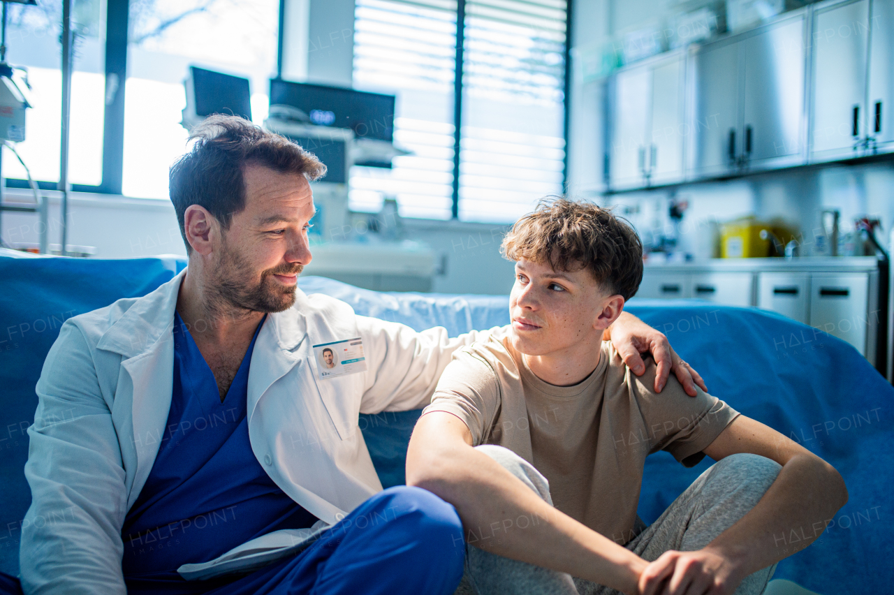Compassionate doctor supporting anxious teenage patient before surgery. Mental health evaluation for depressed teen boy.