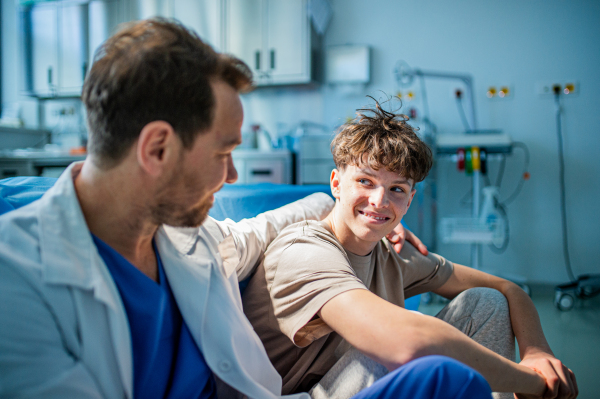 Compassionate doctor supporting anxious teenage patient before surgery. Mental health evaluation for depressed teen boy.