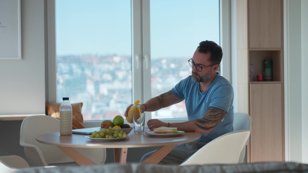 Diabetic man with CGM sensor having healthy breakfast, eating alone at table.