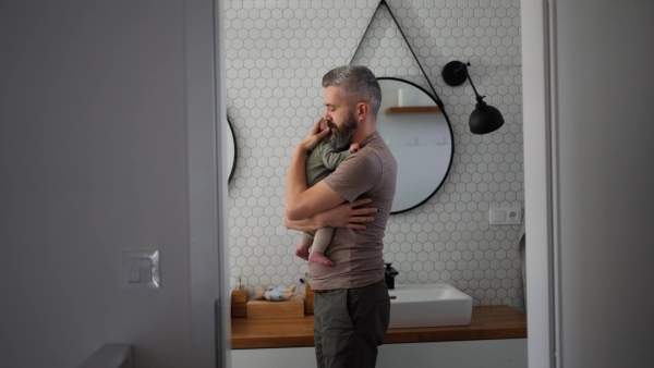 Father comforting his crying baby son, holding him in arms.