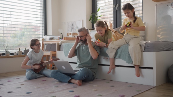 Father with three daughters trying to work from homeoffice. Girl dad concept.