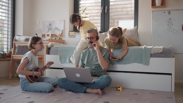 Father with three daughters trying to work from homeoffice. Girl dad concept.